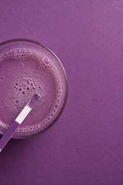 Purple smoothie in bowl with spoon on monochrome background
