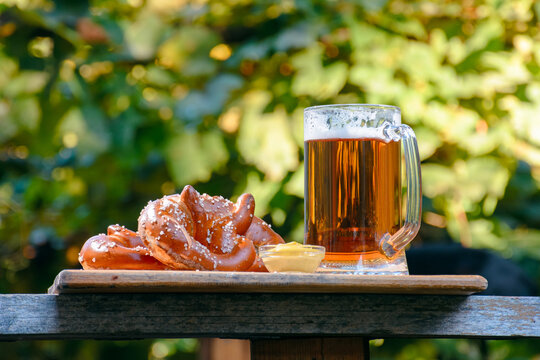 beer and pretzel on a wooden plank. outdoor scenery. oktoberfest holiday design background