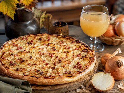 Traditioneller deutscher Zwiebelkuchen mit Speck und goldbraunen Zwiebeln, serviert mit Federwei&szlig;em und frischen Zwiebeln &ndash; rustikale Spezialit&auml;t f&uuml;r den Herbst.