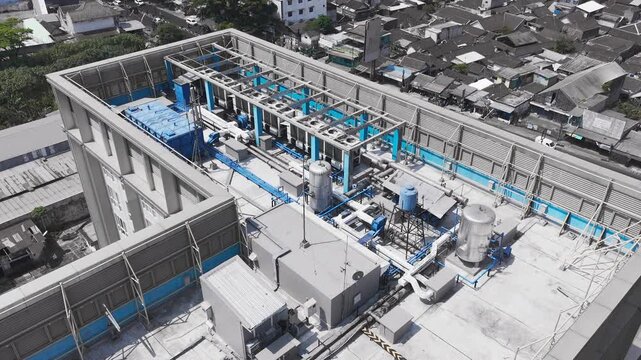 Aerial drone view of rooftop cooling infrastructure at a data center, featuring multiple industrial cooling units, ventilation fans, connected piping, and mechanical equipment supporting high-performa