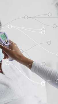 Animation of dots forming abstract pattern over female nurse checking temperature of patient