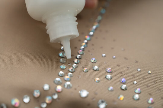 A woman decorates a gymnastics costume with rhinestones. Rhythmic gymnastics. Glue in a tube.