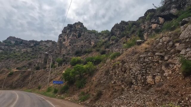 Mountain road curves in wide view through rugged rock formations in Turkey, showing scenic driving, geological terrain, transport infrastructure, and overland tourism in a remote highland corridor