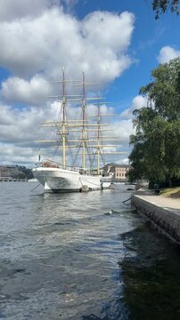 Vertical format 9:16 footage of the historic three-masted full-rigged ship af Chapman moored along the Skeppsholmen waterfront in Stockholm, Sweden.