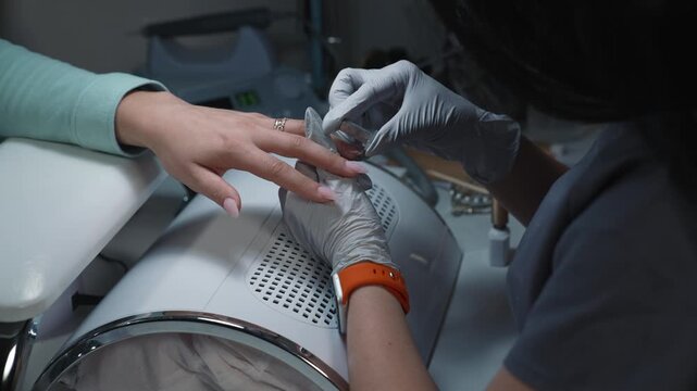 Forming abstract magnetic glitter pattern on nail immediately after gel application during professional manicure procedure in beauty salon