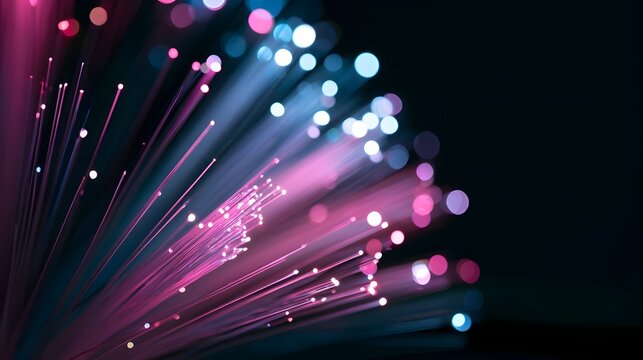 Glowing fiber optic strands radiate vibrant pink and blue light against a dark background in a close up ro view