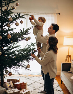 Family decorating a christmas tree with a small child