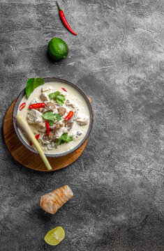 Thai chicken mushroom coconut milk soup tom kha gai in gray bowl with thai spices. Top view
