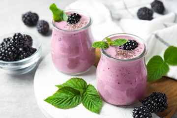 Tasty blackberry smoothies with chia seeds, berries and leaves on light grey table, closeup © New Africa