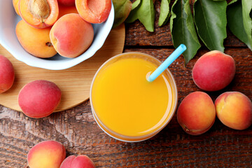 Apricot juice in glass, fresh fruits and leaves on wooden table, flat lay © New Africa