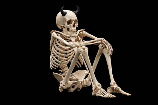 Skeleton wearing devil horns lounging on the floor on black background, Halloween humor portrait