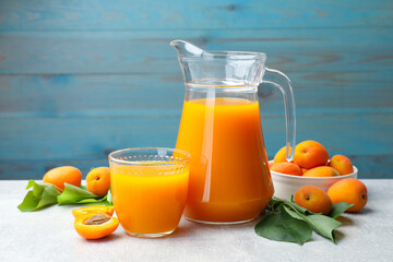 Apricot juice, fresh fruits and leaves on light table © New Africa