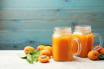 Apricot juice in mason jars, fresh fruits and leaves on light table, space for text © New Africa