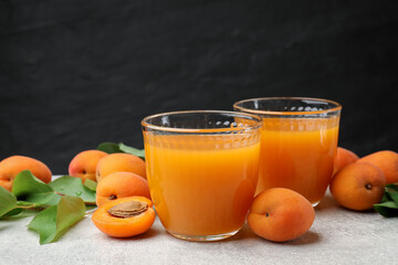 Apricot juice in glasses, fresh fruits and leaves on light table, closeup © New Africa