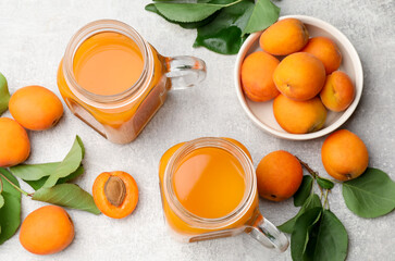 Apricot juice in mason jars, fresh fruits and leaves on light table, flat lay © New Africa