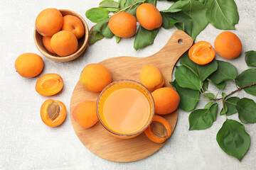 Apricot juice in glass, fresh fruits and leaves on light table, flat lay © New Africa