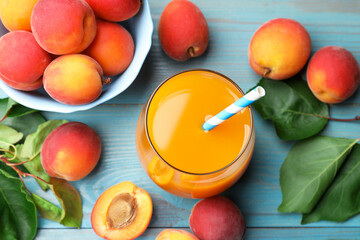 Apricot juice in glass, fresh fruits and leaves on light blue wooden table, above view © New Africa