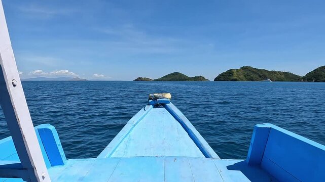 View of Labuan Bajo Harbor and Blue Boat Sailing Near Flores Island, Indonesia, Tropical Coastal Landscape.  
