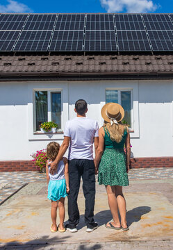 A family looks at solar panels on the roof of a house. Selective focus.