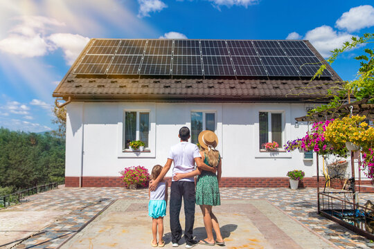 A family looks at solar panels on the roof of a house. Selective focus.