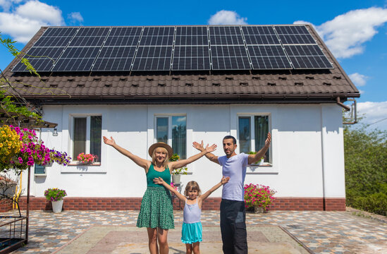 A family looks at solar panels on the roof of a house. Selective focus.