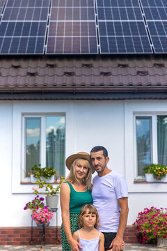 A family looks at solar panels on the roof of a house. Selective focus.