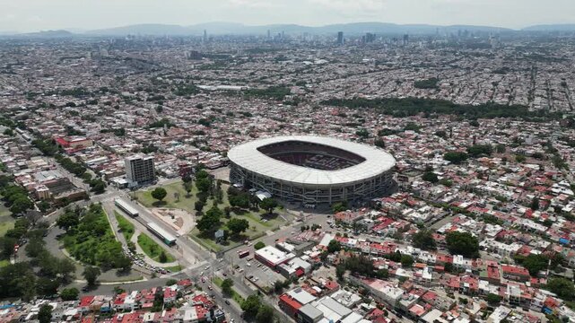 Drone view of Guadalajara featuring Estadio Jalisco and Nuevo Progreso Bullring, surrounded by residential areas and city infrastructure.
