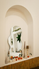 Naklejka premium Cozy autumn display with decorative houses, pumpkins, and candles in an arched niche