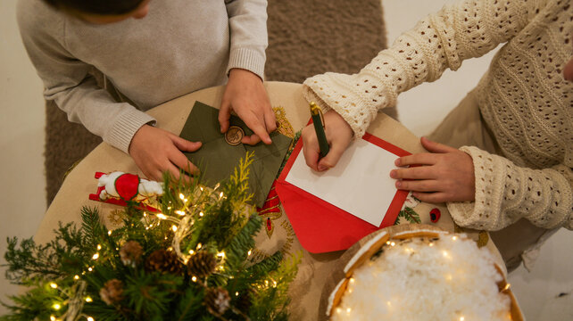 Children writing holiday cards with festive decorations and warm lighting