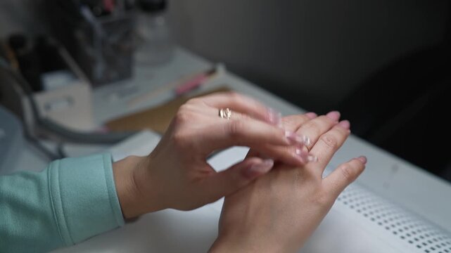 Client gently rubbing applied nourishing oil into cuticles after completing nail extension procedure in beauty salon