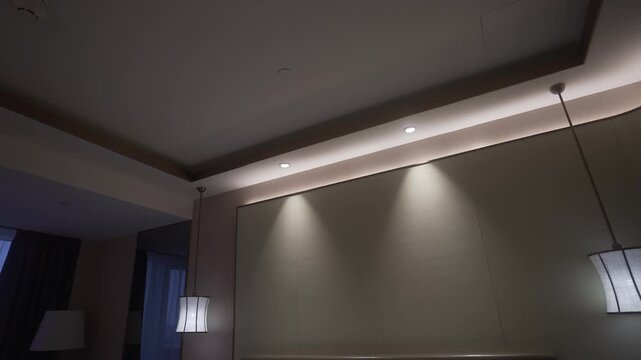 Low-angle hotel bedroom ceiling with cove lighting, recessed downlights, and illuminated pendant lamps, with ceiling, cove, lighting, recessed detail, showing downlight, pendant, lamp, shade context