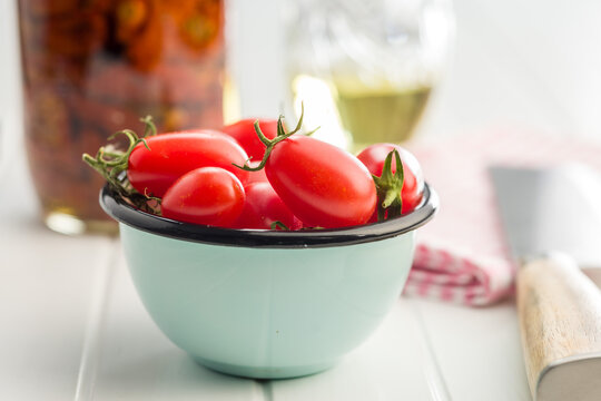Fresh Red Cherry Tomatoes in a Blue Enamel Bowl on a Rustic Wooden Table