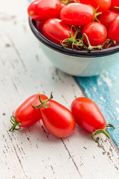Fresh Red Tomatoes in an Enamel Bowl on a Rustic Wooden Table . Close-Up Food Still Life