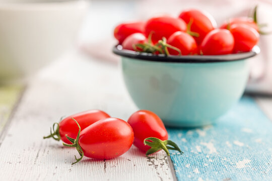 Fresh Red Tomatoes in an Enamel Bowl on a Rustic Wooden Table . Close-Up Food Still Life