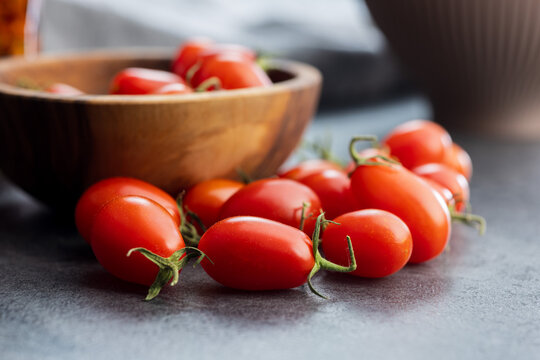 Fresh Cherry Tomatoes Close-Up in Wooden Bowl on Kitchen Surface. Red Healthy Produce