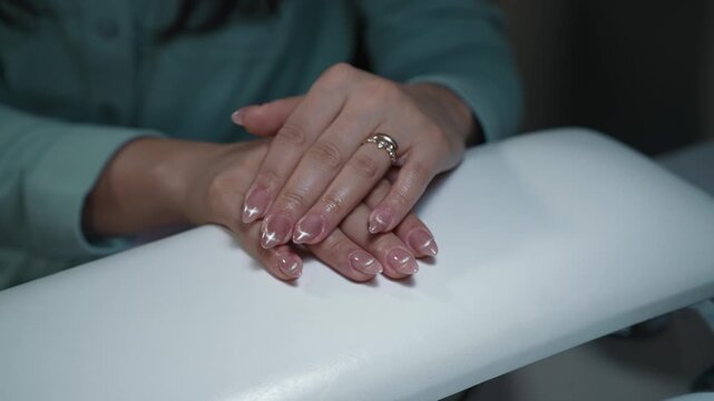 Client&rsquo;s neatly folded hands showcase final result of professional nail extension in beauty salon