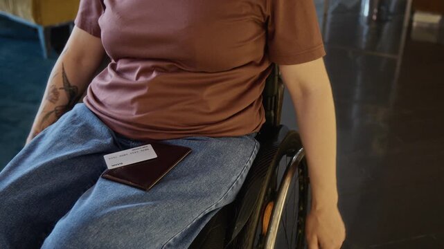 Unknown woman with disability rolling wheelchair forward with passport and credit card on lap. Clip is ideal for inclusive travel, banking, or accessibility marketing campaigns
