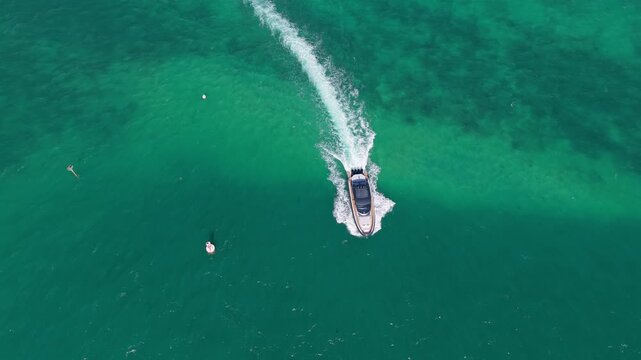 Aerial view captures luxury yacht crossing calm sea. Boat leaves marina with motorboat nearby. Summer destination looks beautiful. Journey continues across blue water