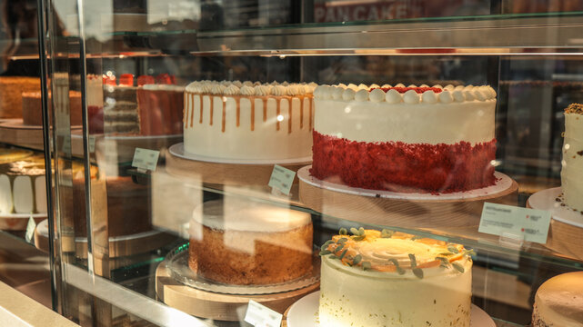 Delicious cakes displayed in a bakery window under soft lighting
