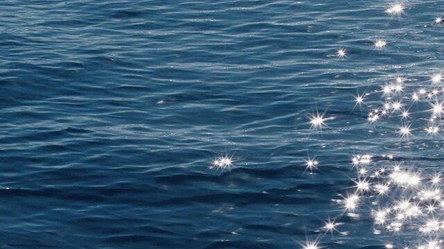 Sea surface with blinking stars and flares as seen from the moving sailing boat