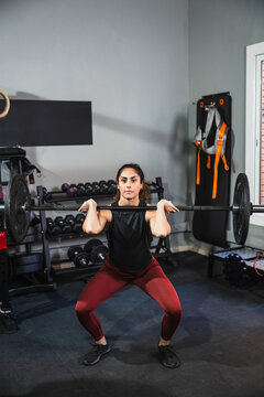 Woman performing front squat with barbell in gym