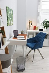 Fototapeta premium Stylish workplace with desk, chair and shelving unit in office. Interior design