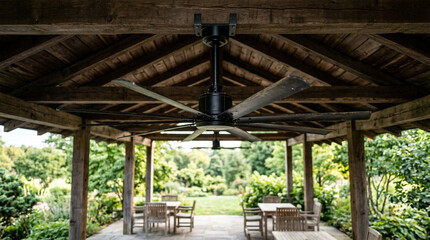 Fototapeta premium Large black industrial ceiling fan on a wooden gazebo structure over an outdoor patio