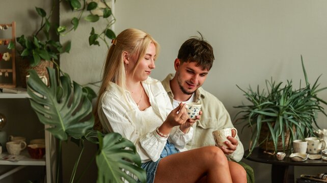 Young couple enjoying coffee together surrounded by lush indoor plants