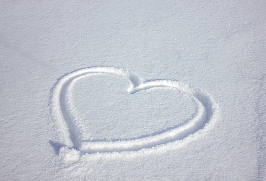 Heart Shape Drawn in Fresh Snow, Winter Love Concept, Romantic Snowy Background with Soft Natural Light with copy space.