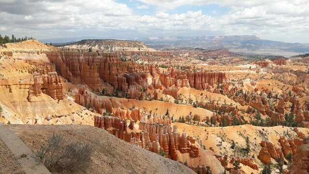 Wide view of orange hoodoos beneath summer clouds