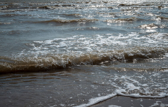 Closeup view of sea waves with foam and shimmering reflections on the water surface