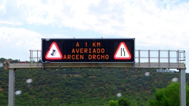 An electronic road information sign above the A-1 motorway in Spain, warning drivers of a broken-down car 1 km away and advising them to take care when crossing.August 22, 2026