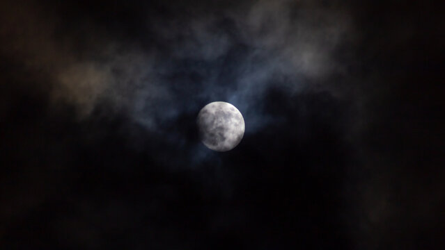 Full moon in the night sky with clouds