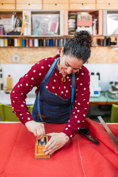 Woman marking red fabric with chalk marker